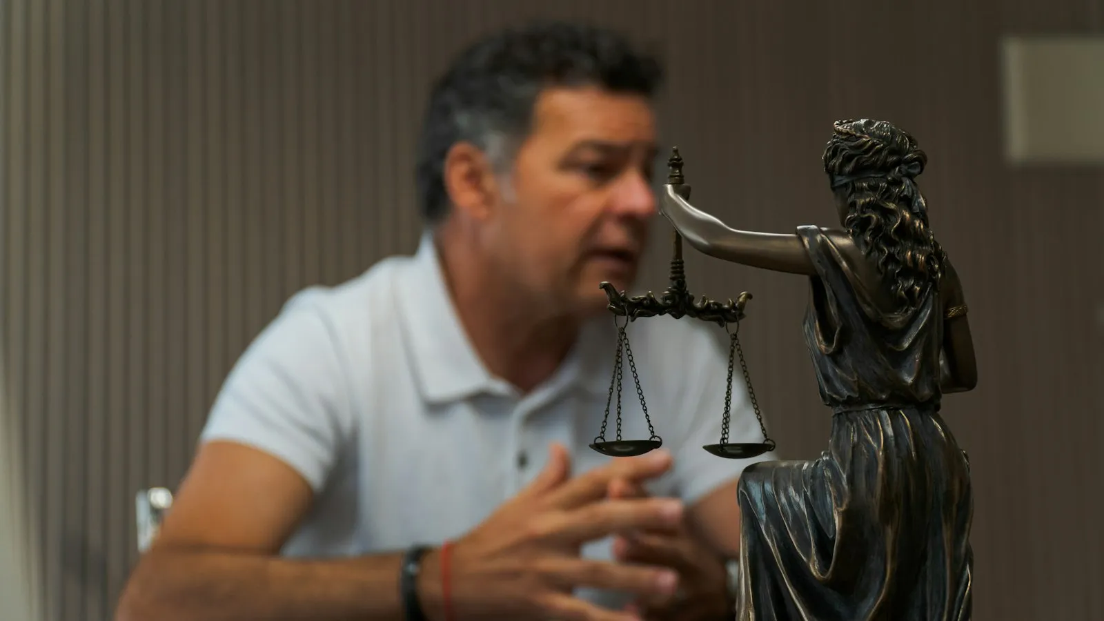 Cliente en consulta con un abogado, con una estatua de la justicia en primer plano