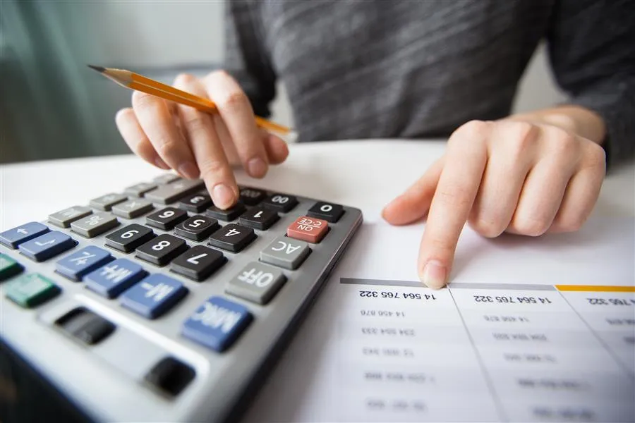 Persona calculando su declaración de renta con calculadora y documentos