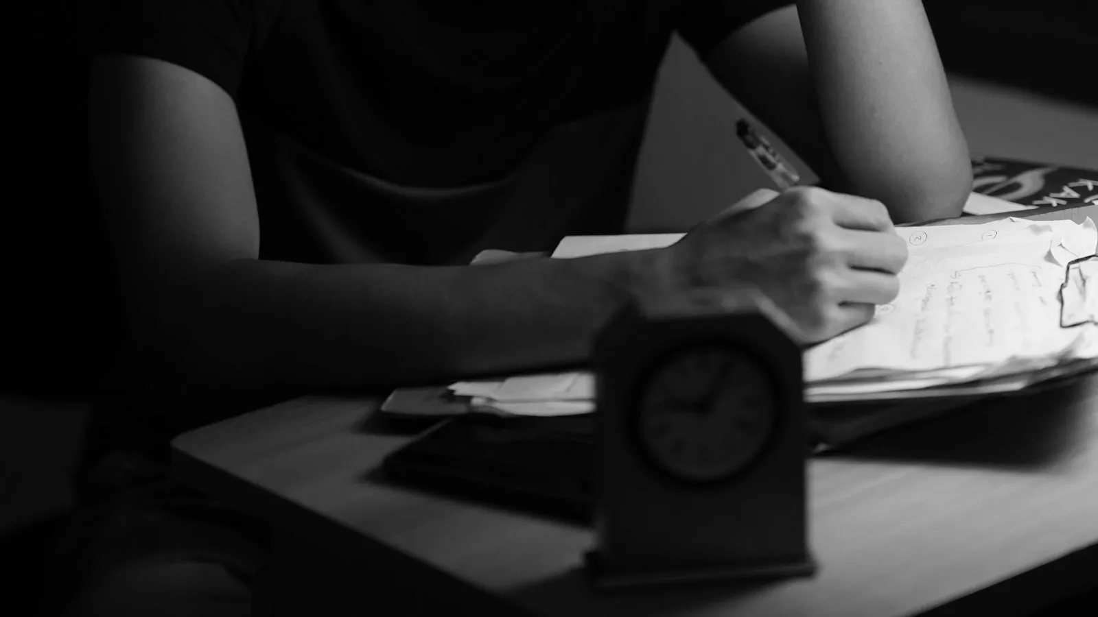 Persona diligenciando documentos con un reloj en primer plano